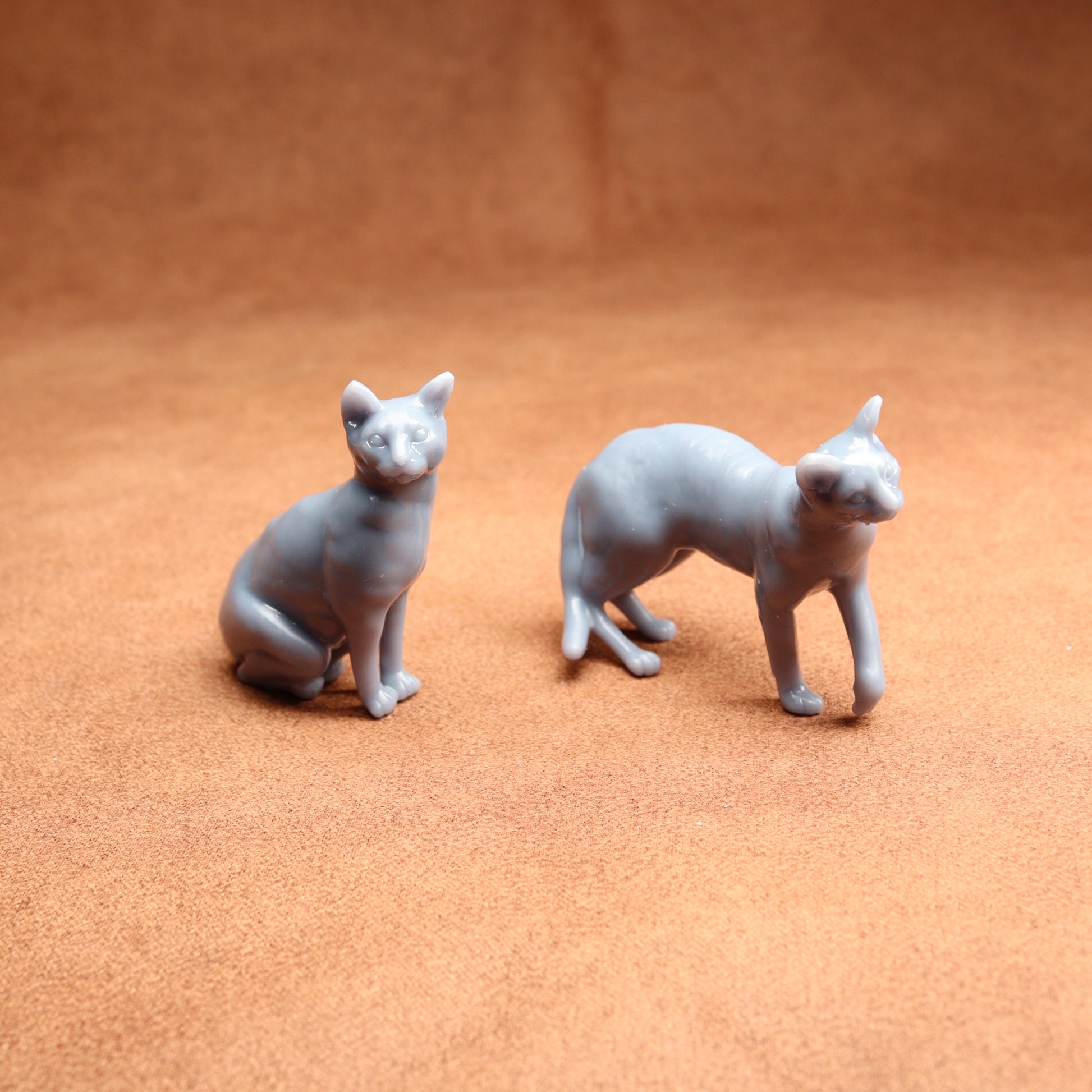 Two gray cat figurines on a brown surface