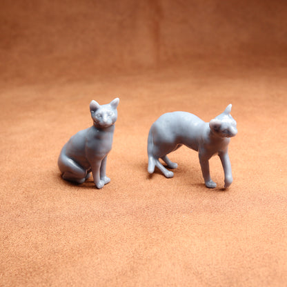 Two gray cat figurines on a brown surface