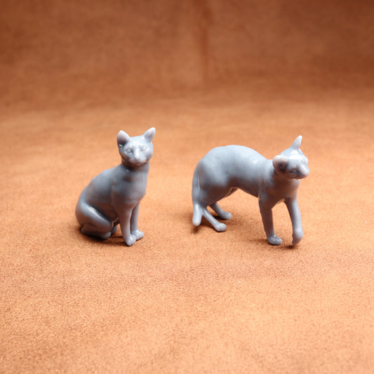 Two gray cat figurines on a brown surface
