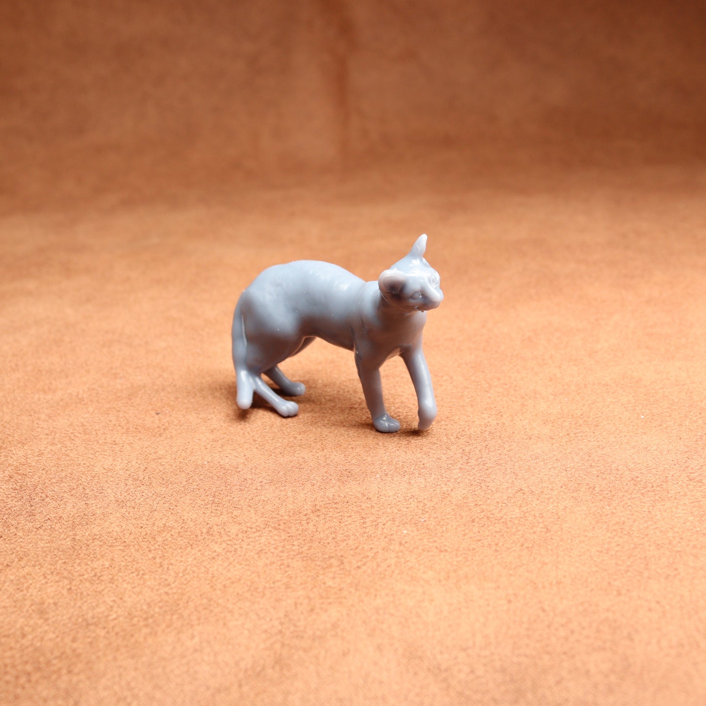 Small gray cat figurine on a brown surface
