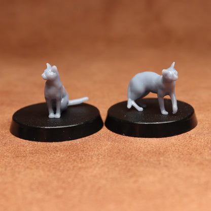 Two miniature cat figurines on black bases against a brown background