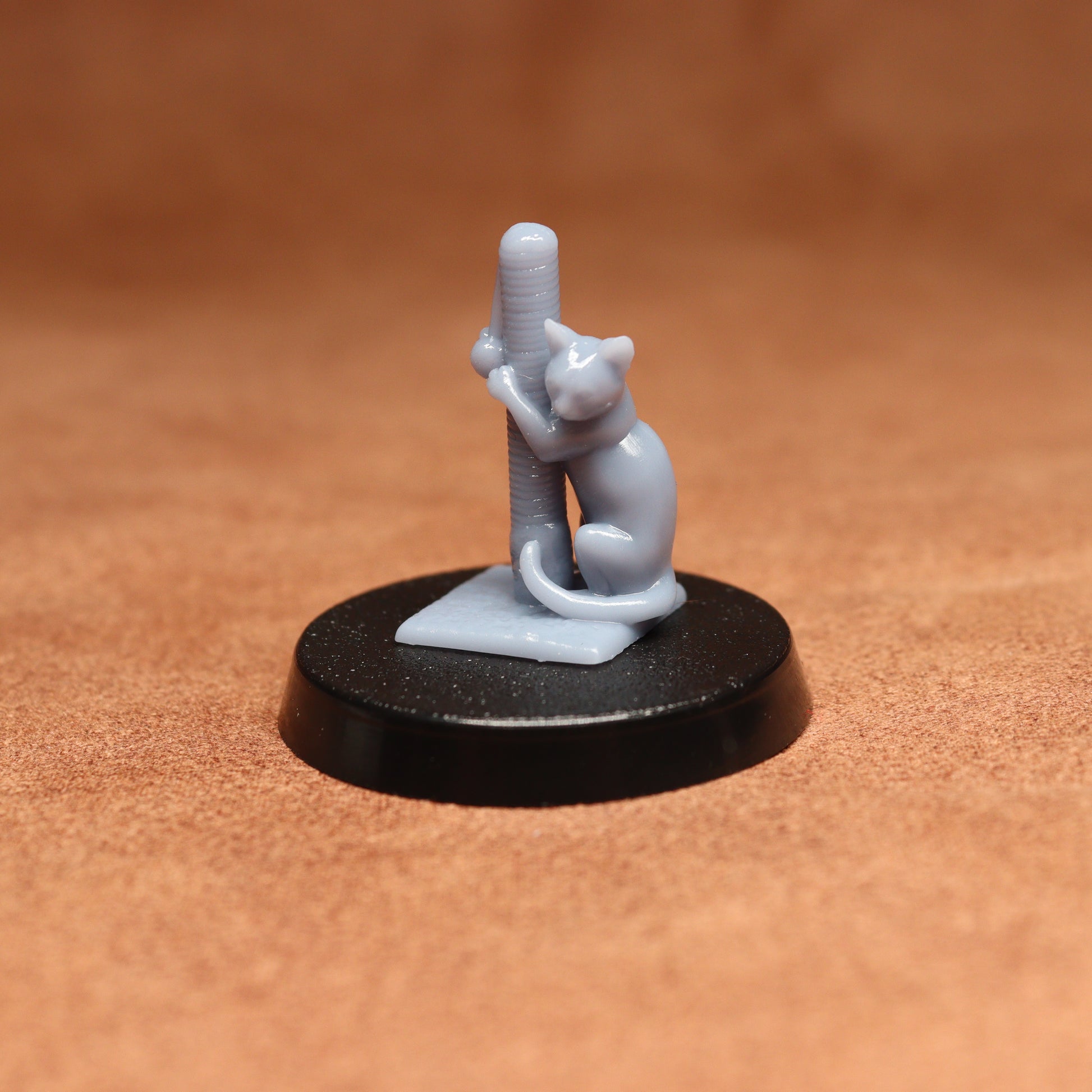Small figurine of a cat climbing a pole on a black base against a brown background