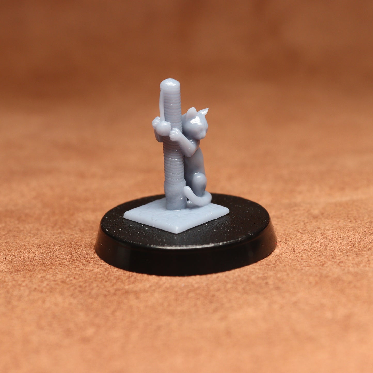 Small figurine of a cat climbing a cactus on a brown surface