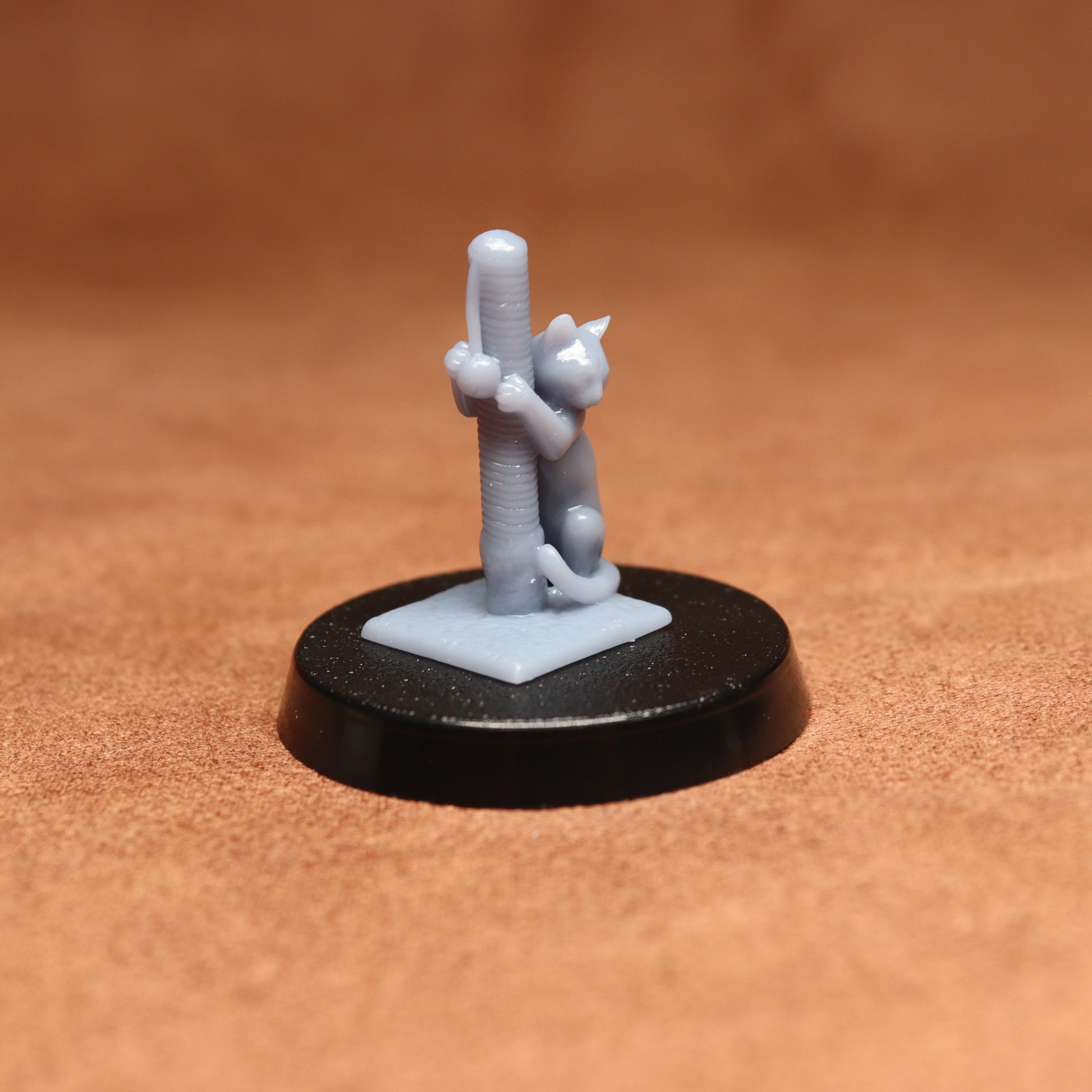 Small figurine of a cat climbing a cactus on a brown surface