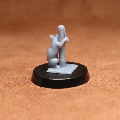 Small figurine of a cat climbing a pole on a black base against a brown background