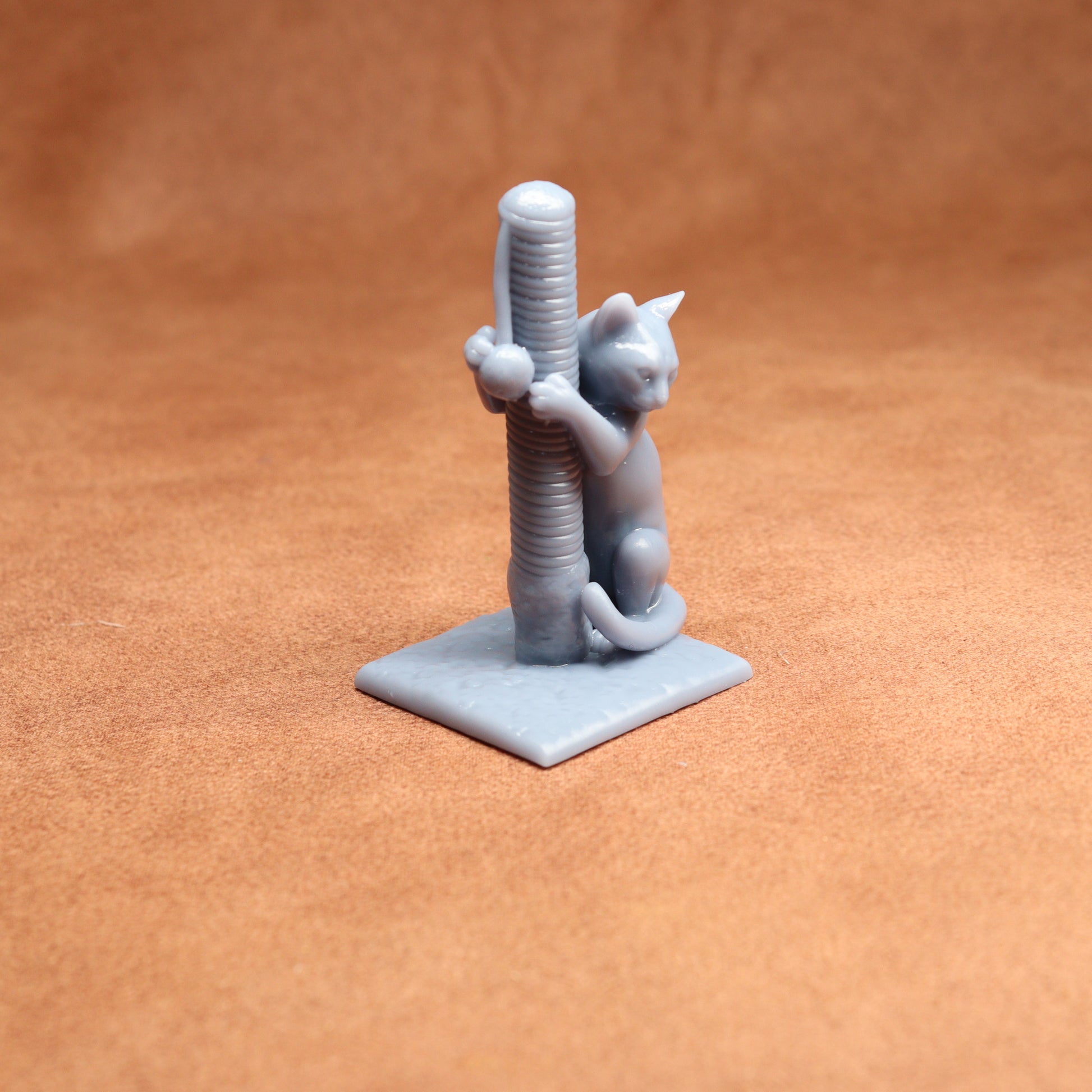 3D-printed model of a cat climbing a scratching post on a brown surface