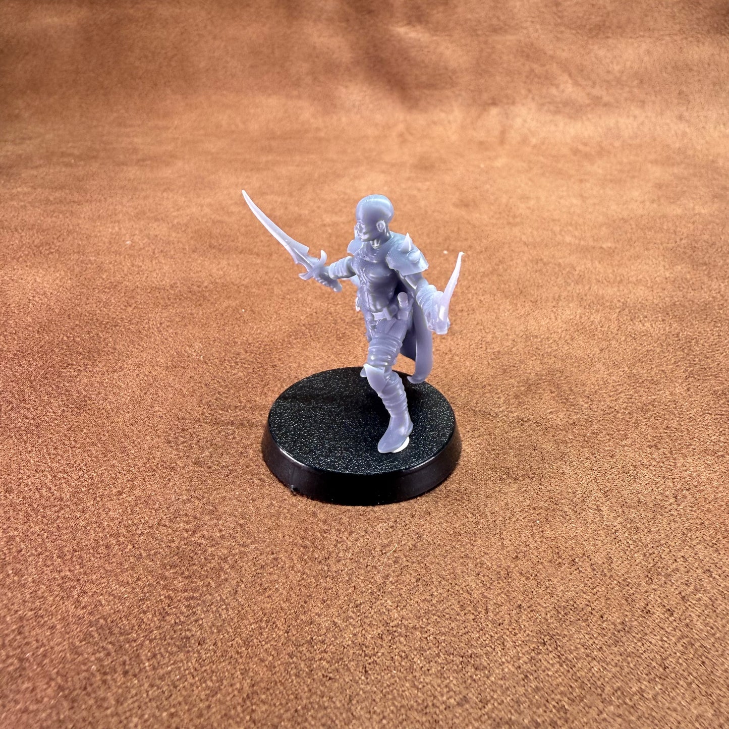 Miniature figurine on a round black base against a brown textured background