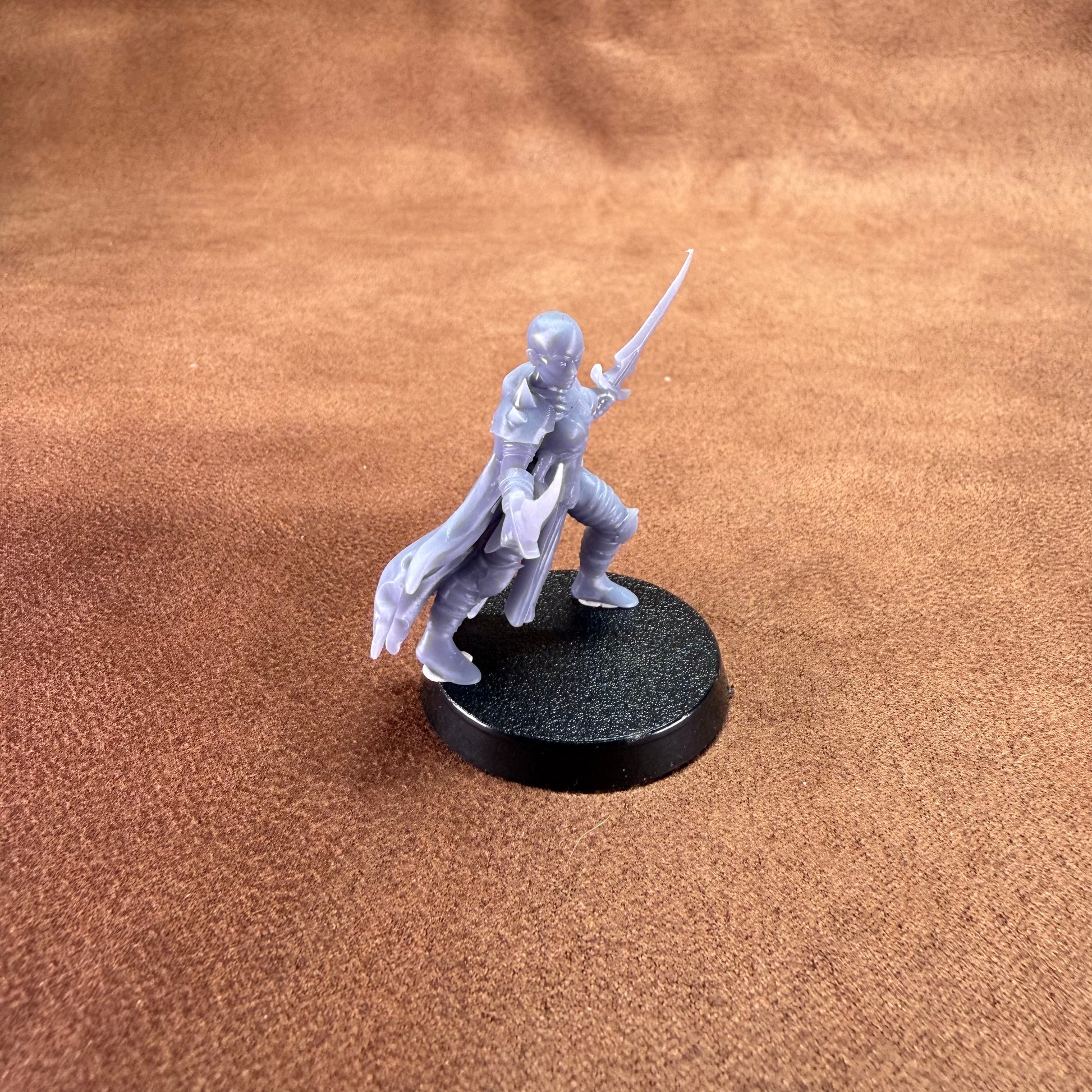 Miniature figurine on a round black base against a brown textured background
