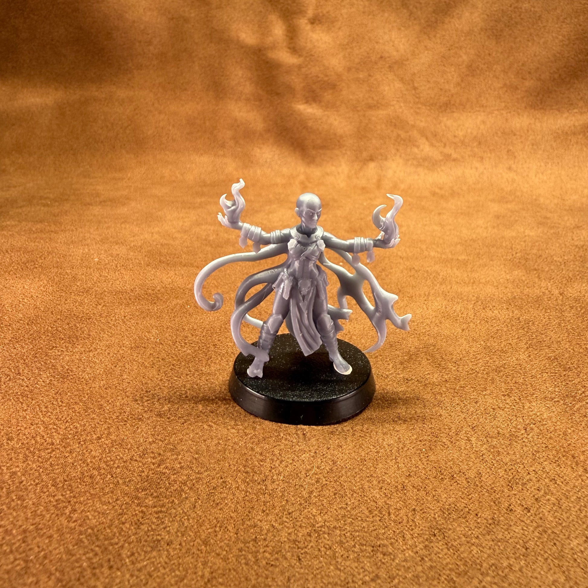 Minature figurine with tentacle-like appendages on a brown surface