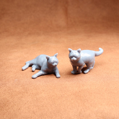 Two small gray cat figurines on a brown surface