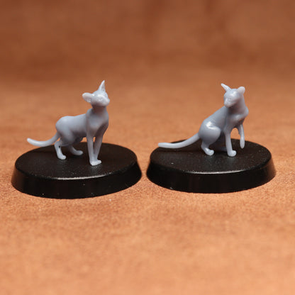 Two gray cat figurines on black bases against a brown background