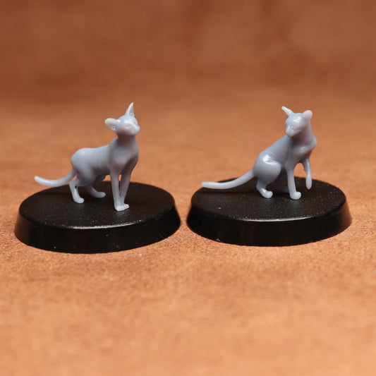 Two gray cat figurines on black bases against a brown background