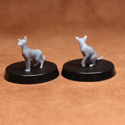 Two gray cat figurines on black bases against a brown background