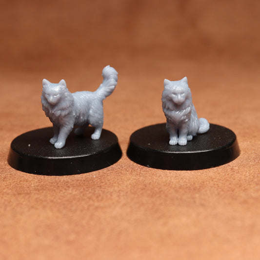 Two miniature cat figurines on black bases against a brown background
