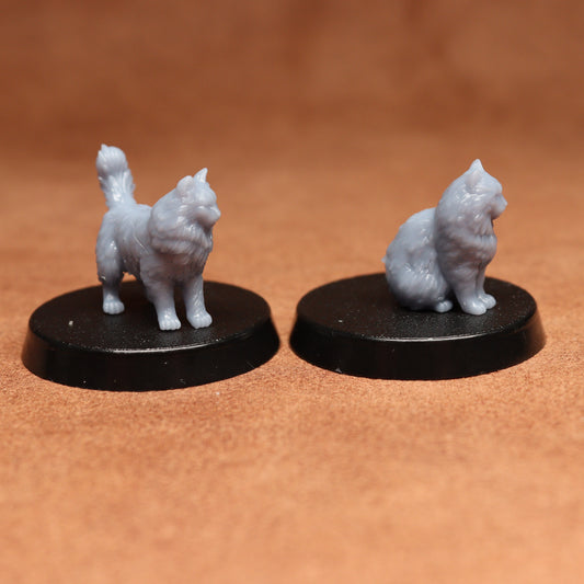 Two miniature cat figurines on black bases against a brown background