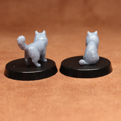 Two miniature cat figurines on black bases against a brown background