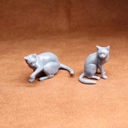Two small gray cat figurines on a brown surface