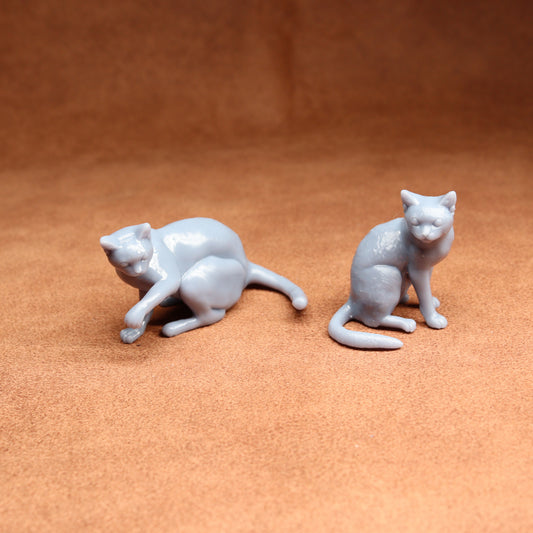Two small gray cat figurines on a brown surface