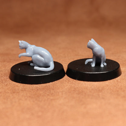 Two miniature cat figurines on black bases against a brown background