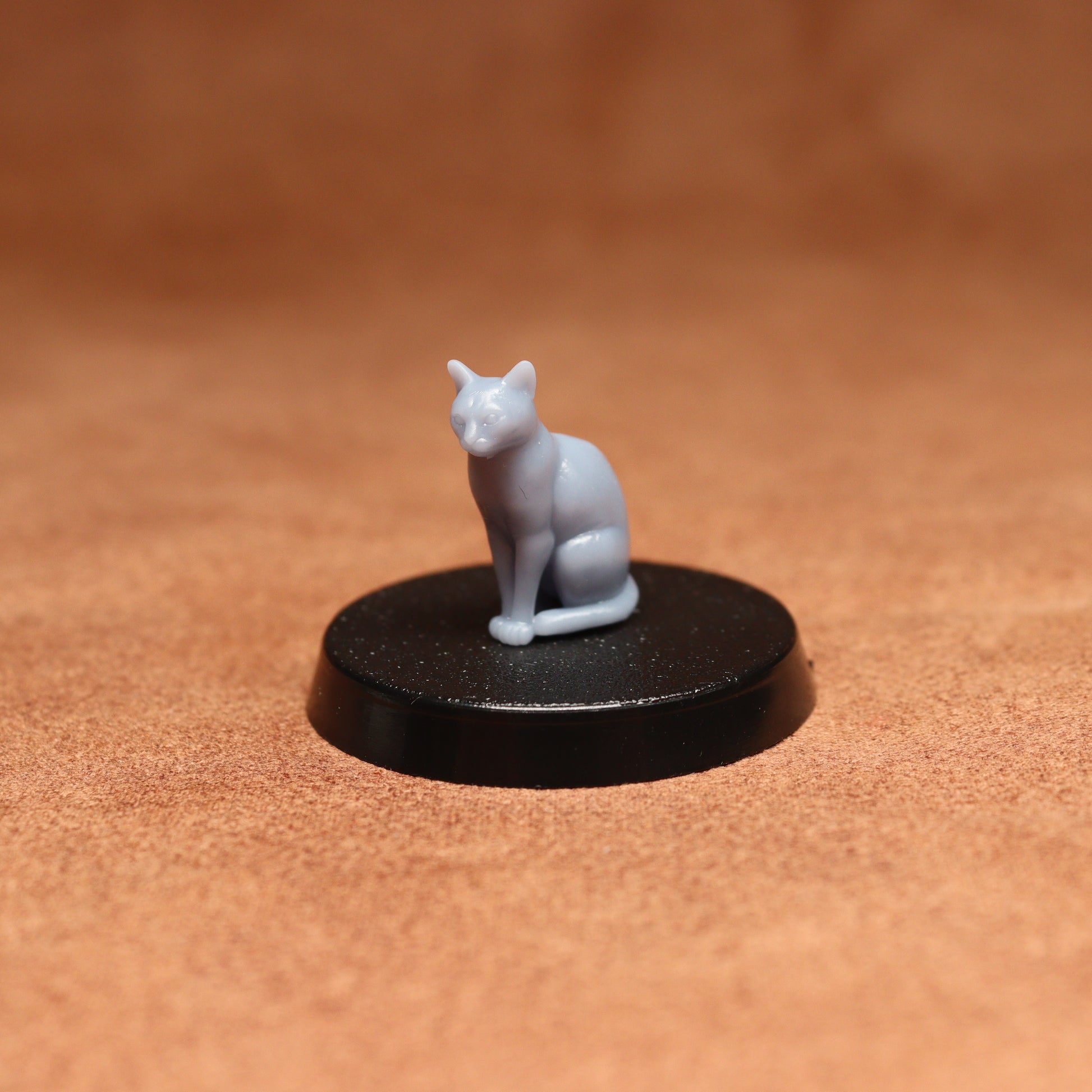 White cat figurine on a black round base against a brown background