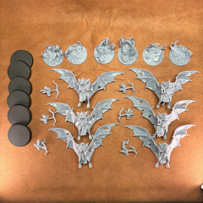 Collection of silver bat figurines and round black pads on a brown surface