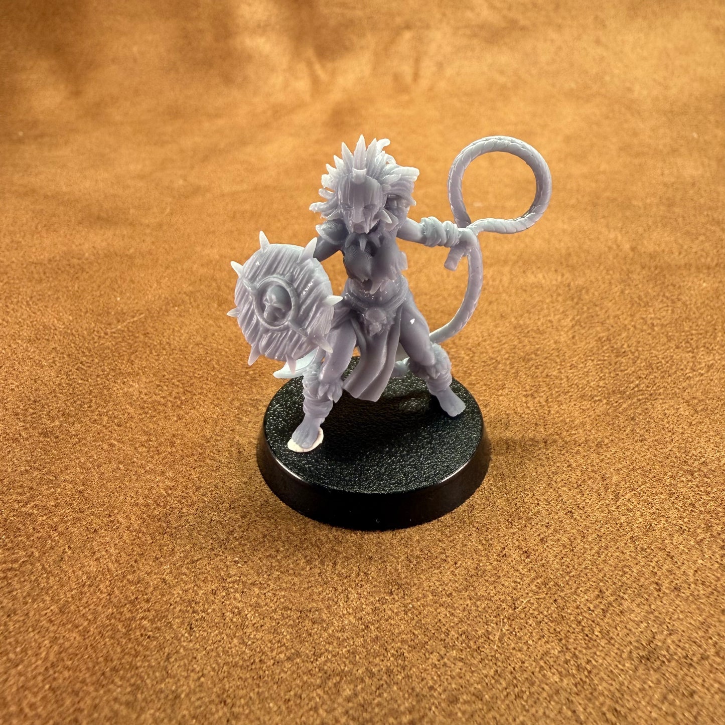 Gray fantasy figurine on a black base against a brown background