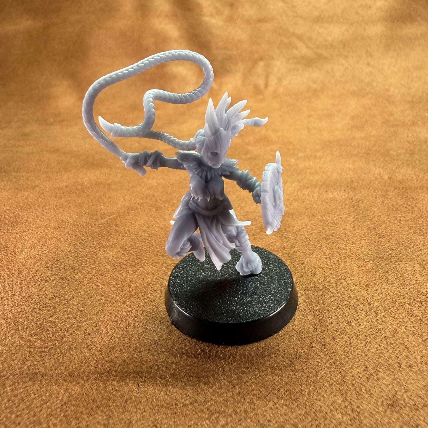 Fantasy figurine on a round black base against a brown background