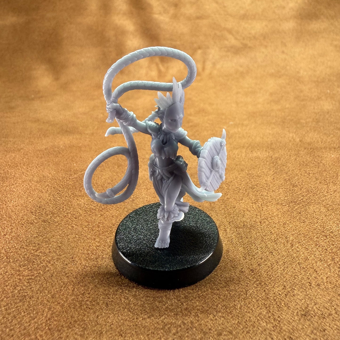 Miniature figurine on a round black base against a brown background