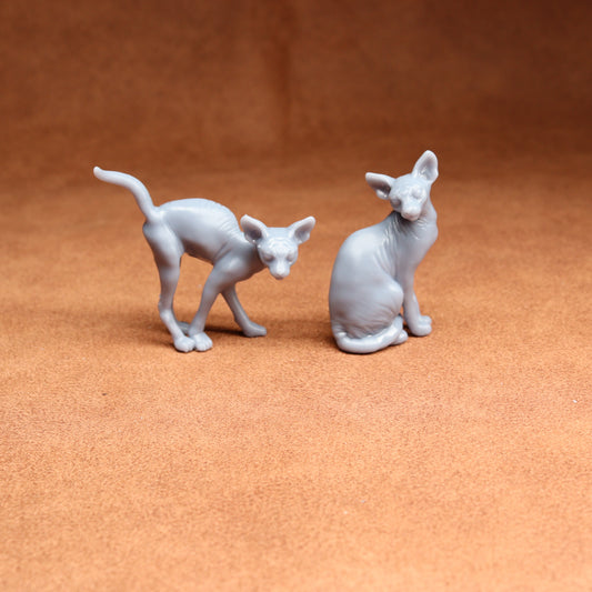 Two gray cat figurines on a brown surface