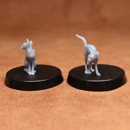 Two miniature cat figurines on black bases against a brown background