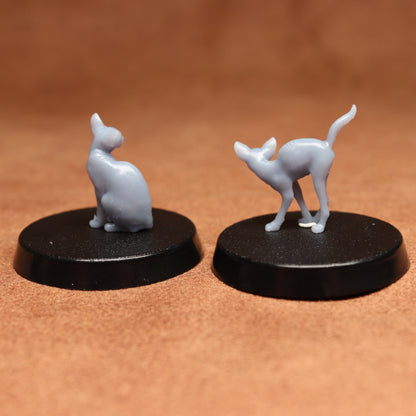 Two gray cat figurines on black bases against a brown background