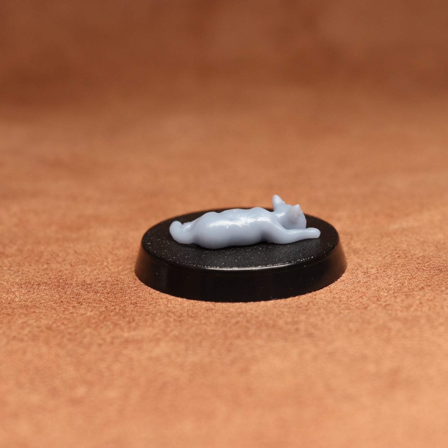 Small white figurine on a black base against a brown background