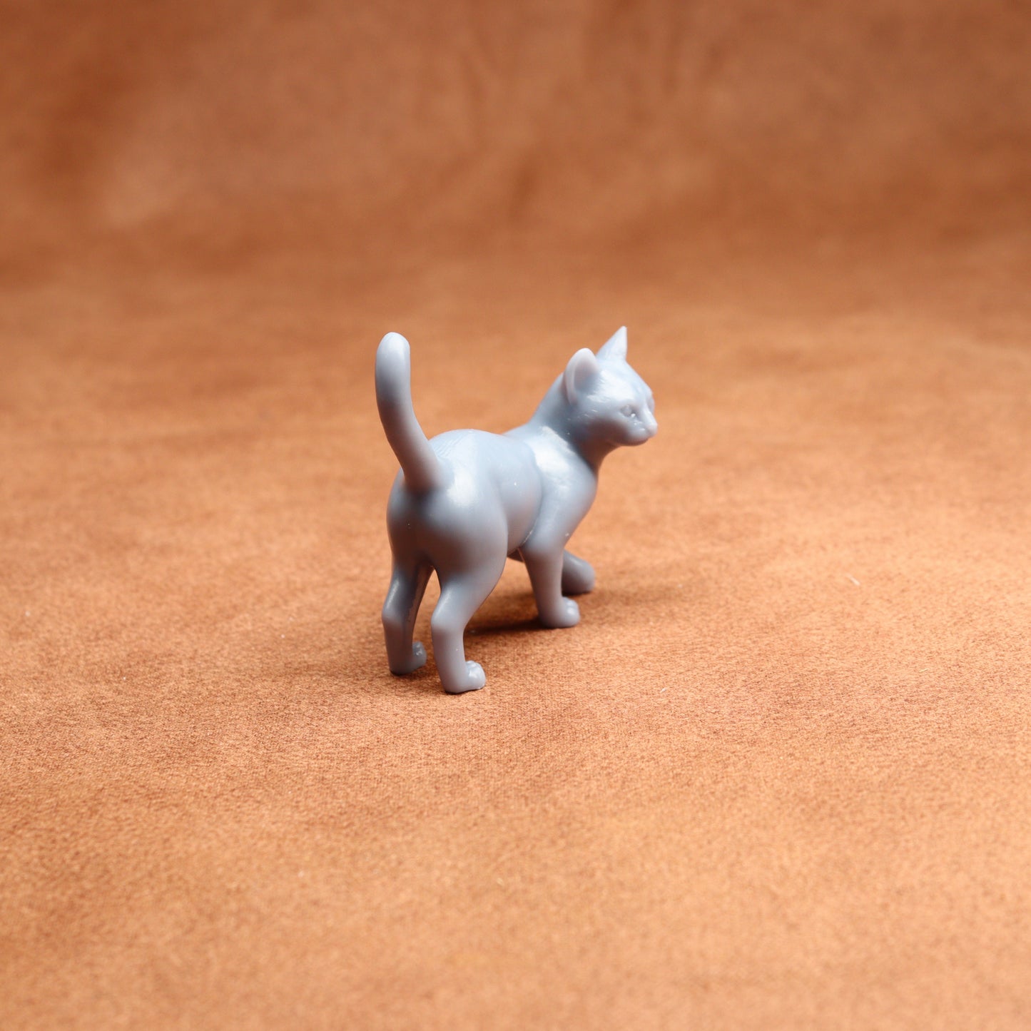Small gray cat figurine on a brown surface