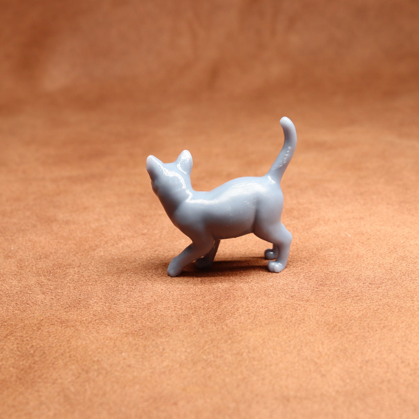 Small white cat figurine on a brown surface