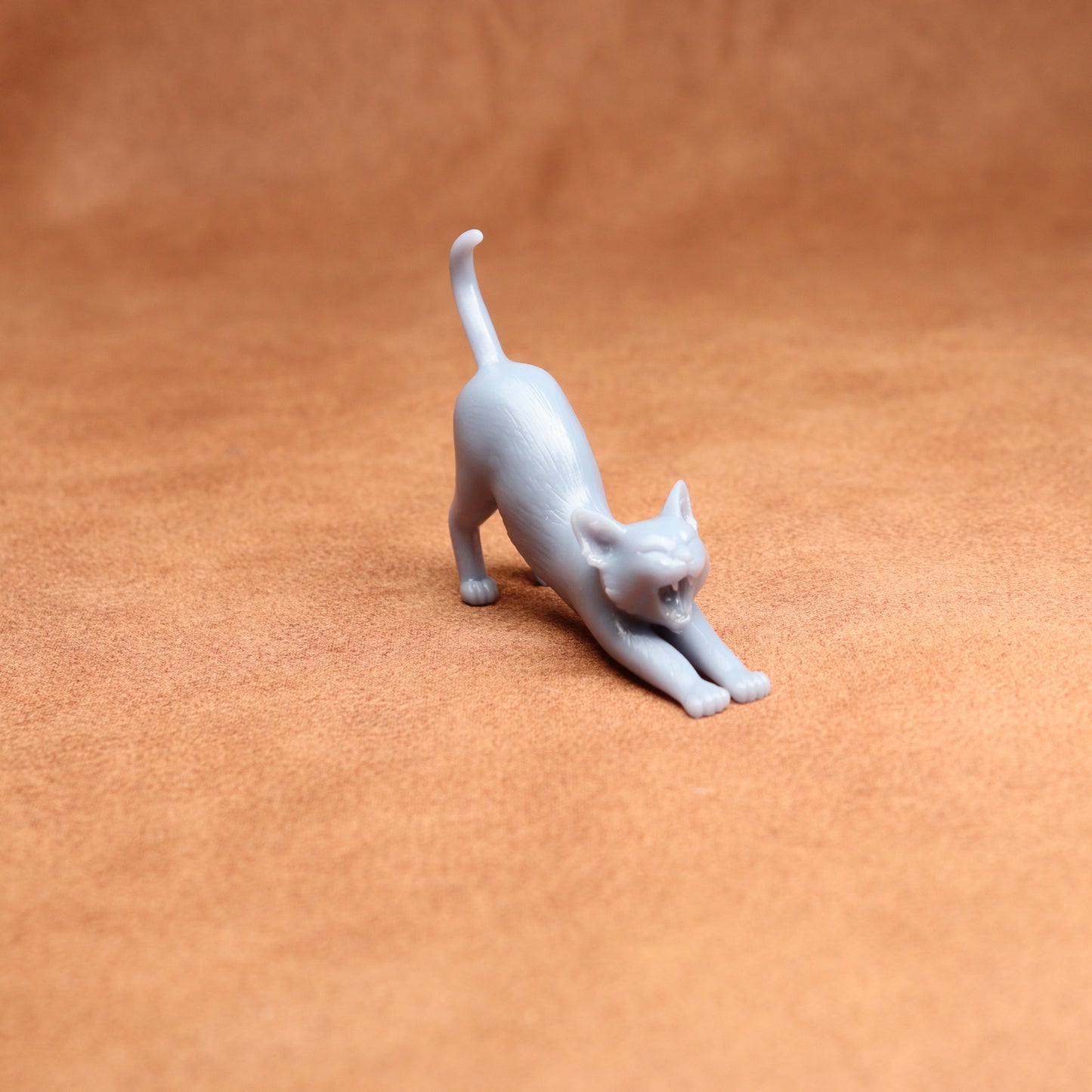 White cat figurine stretching on a brown surface