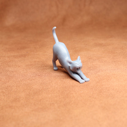 White cat figurine stretching on a brown surface