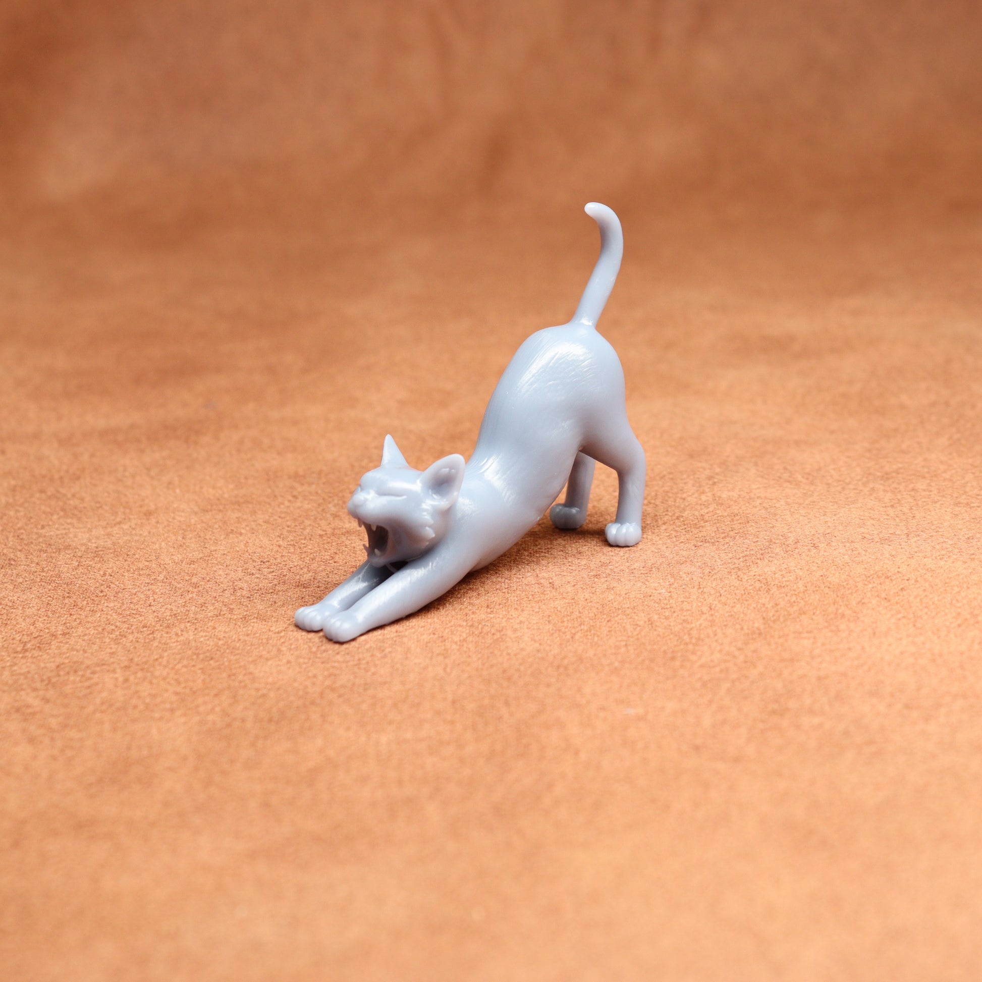 White cat figurine stretching on a brown surface