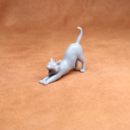 White cat figurine stretching on a brown surface