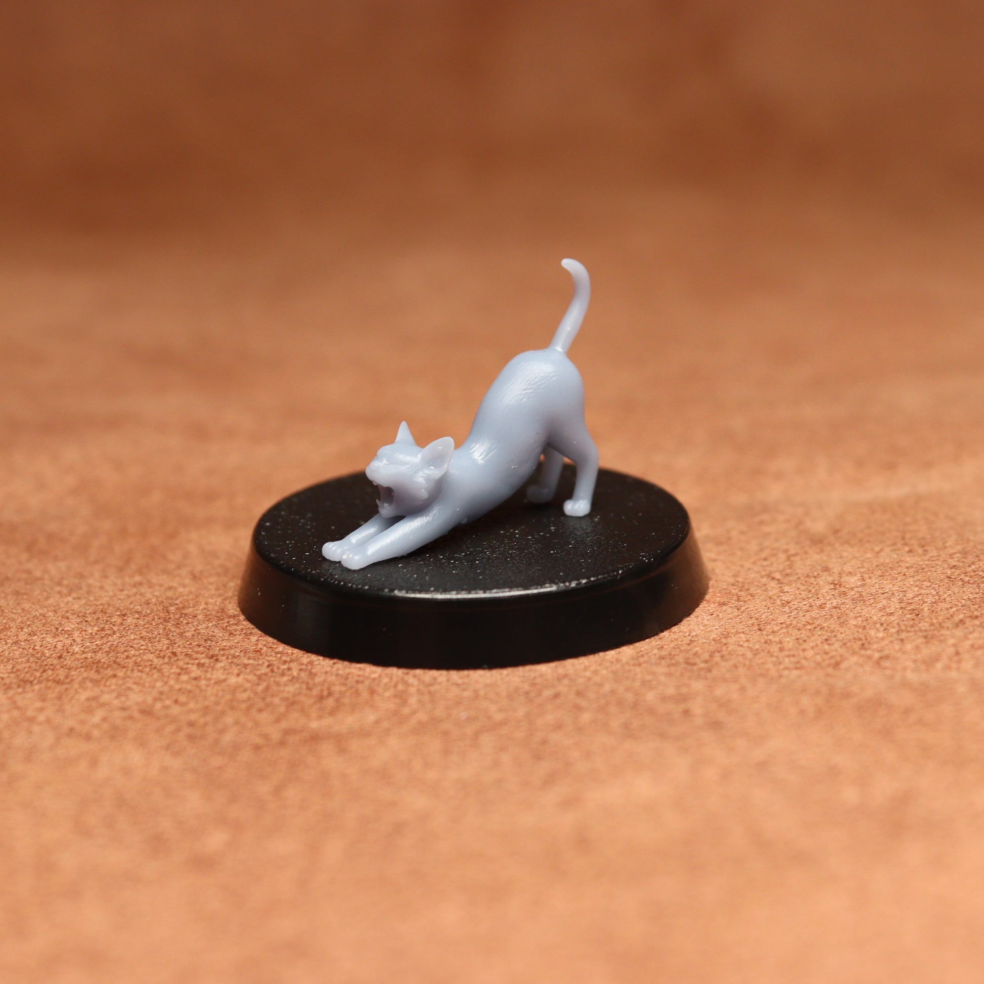White cat figurine on a black round base against a brown background