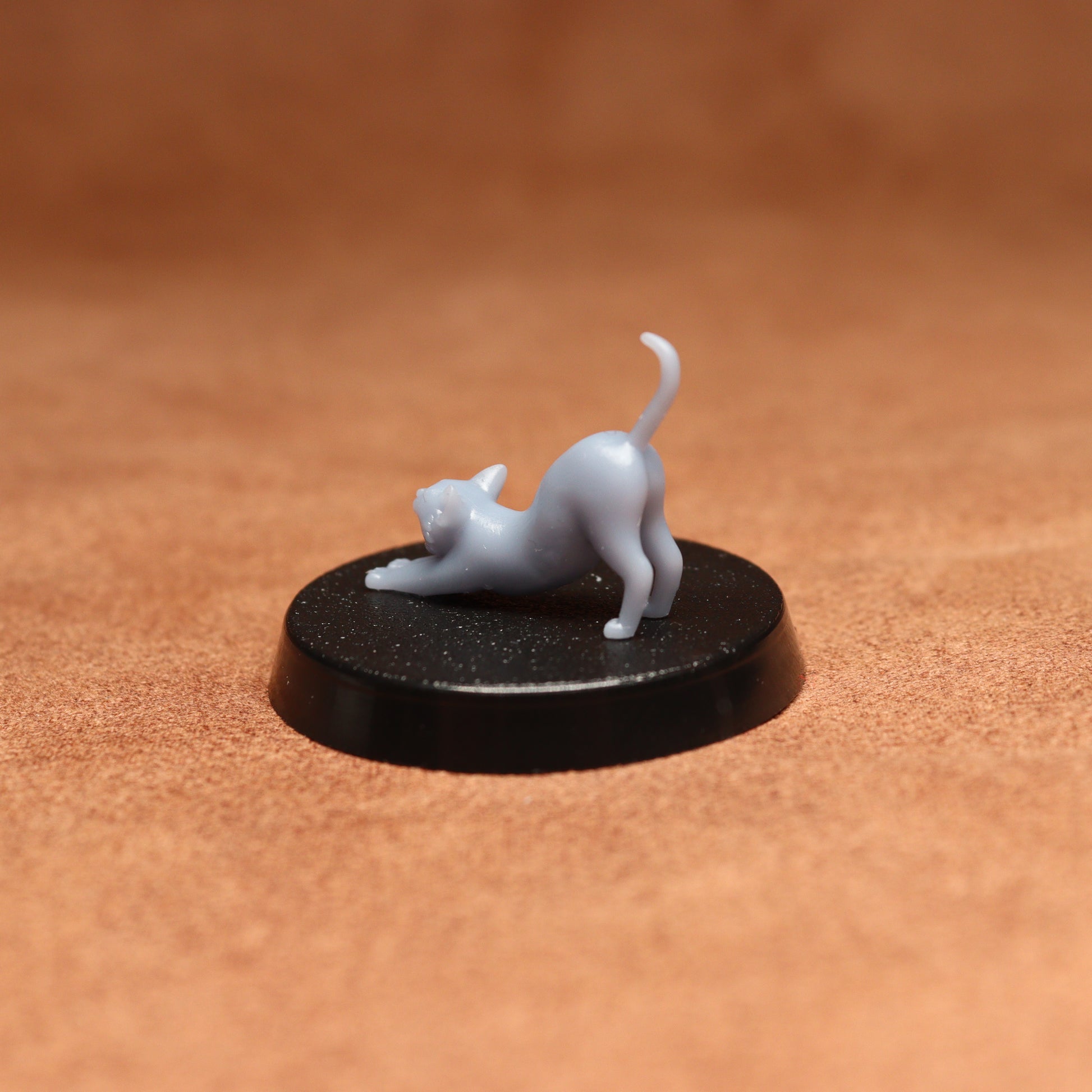 White cat figurine on a black round base against a brown background