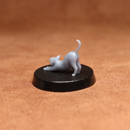 White cat figurine on a black round base against a brown background