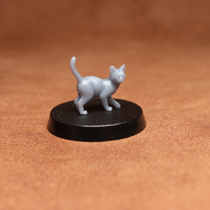 Small white cat figurine on a black round base against a brown background