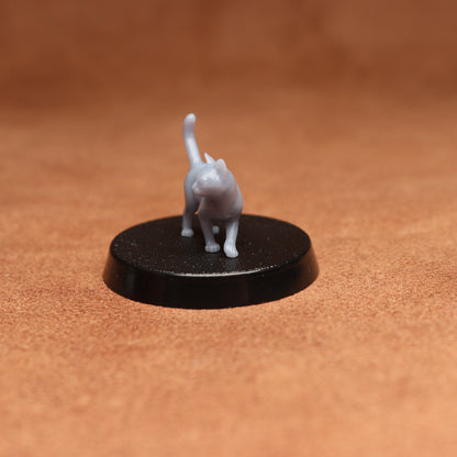 Small gray cat figurine on a black round base against a brown background