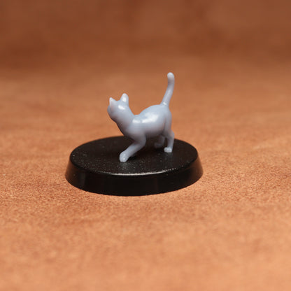 White cat figurine on a black round base against a brown background