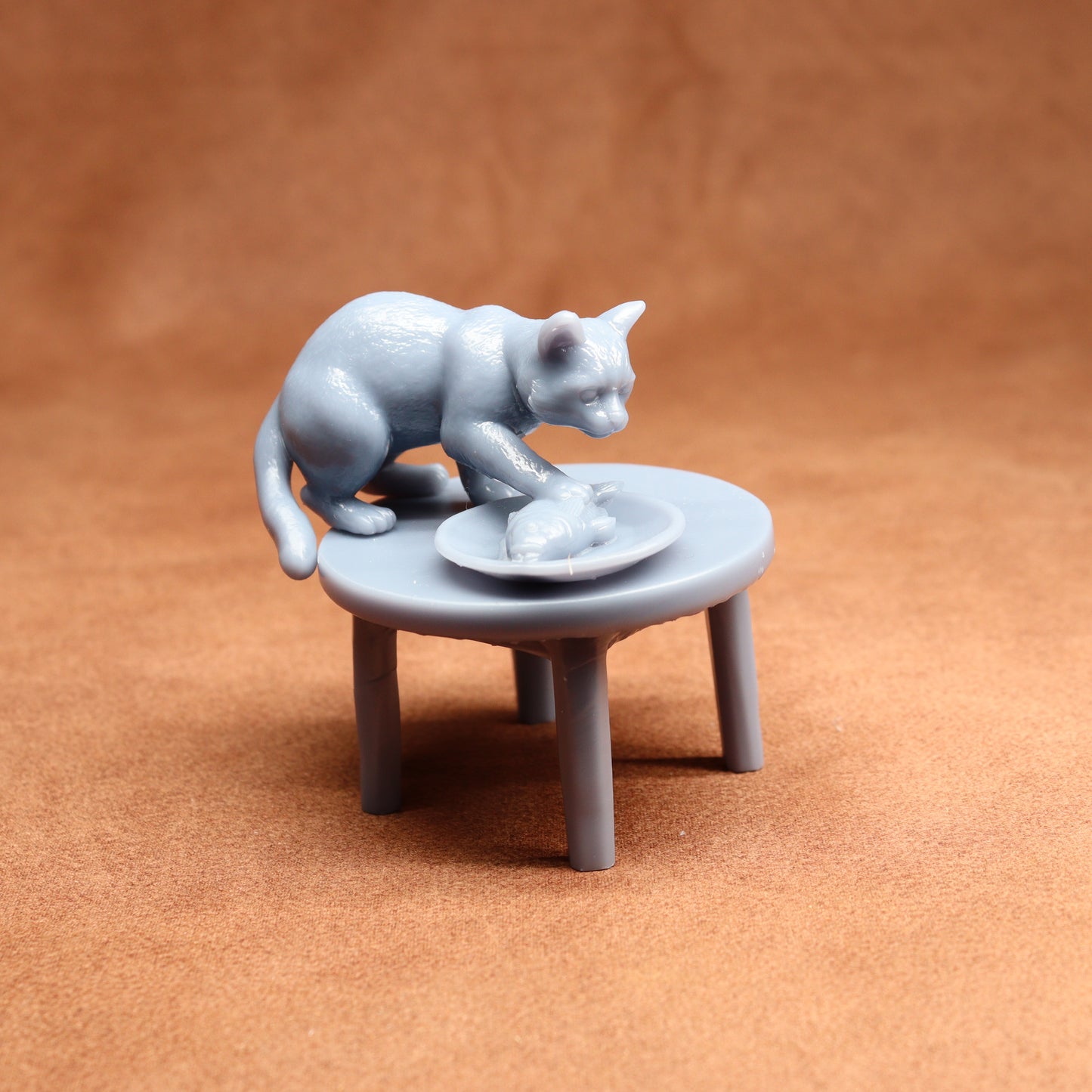 Gray cat figurine on a small table with a ball of yarn on a brown background