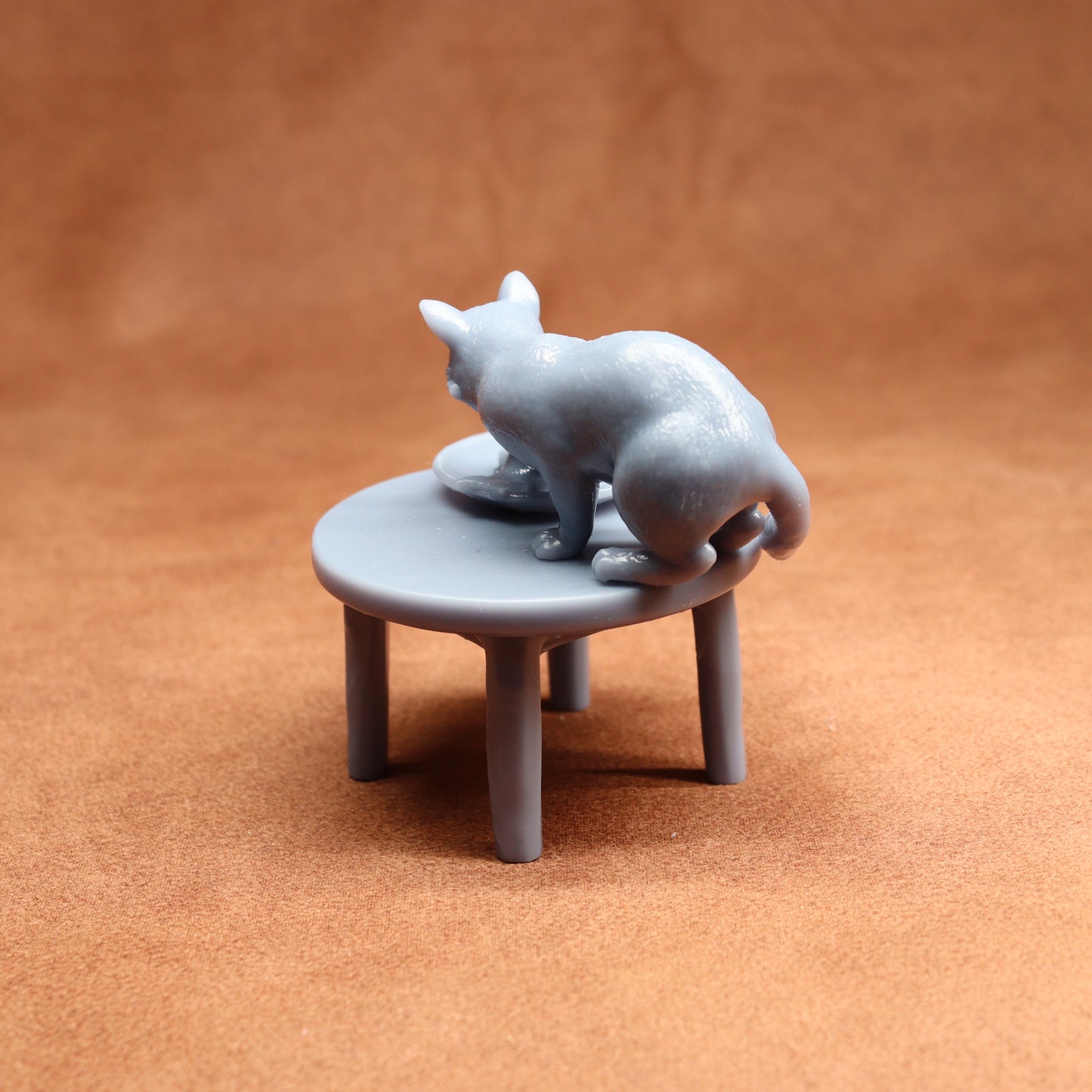 Gray cat figurine on a small round table against a brown background