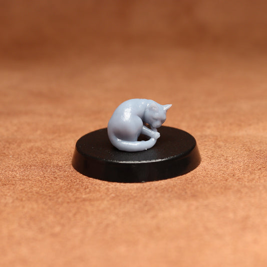 grey resin miniature cat figure on a black base with a brown background