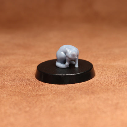 grey resin miniature cat figure on a black base with a brown background