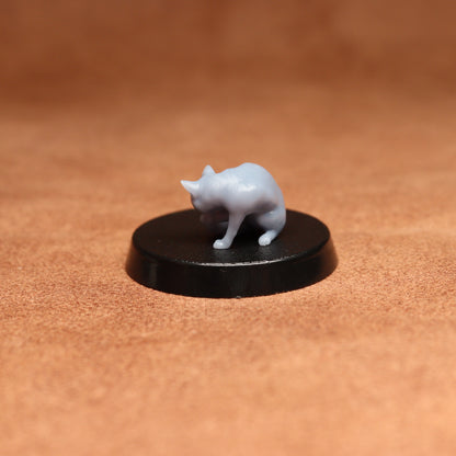 grey resin miniature cat figure on a black base with a brown background