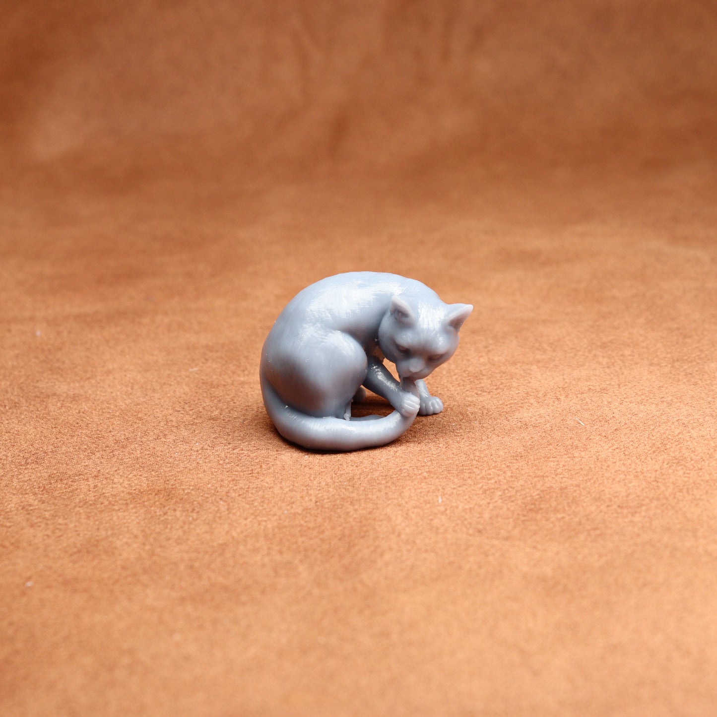 Gray cat figurine on a brown leather surface